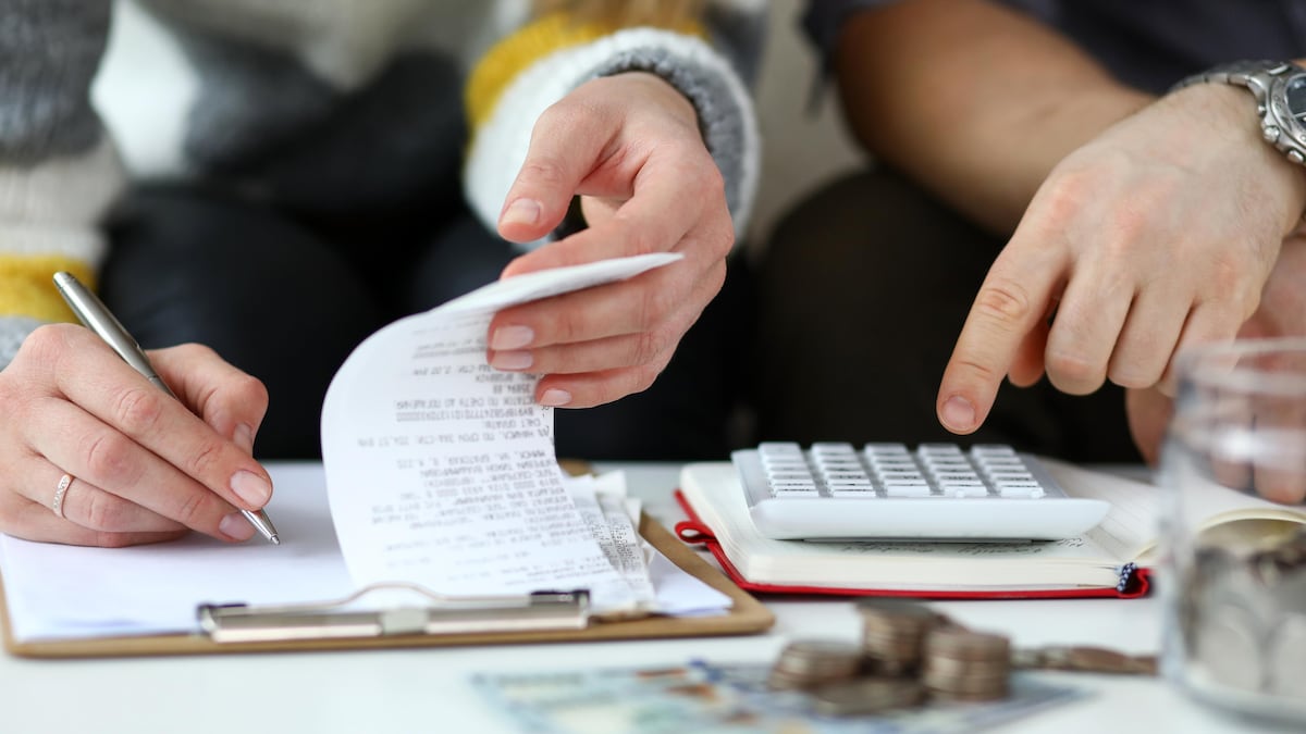 Deux personnes font des calculs avec des factures et une calculatrice.