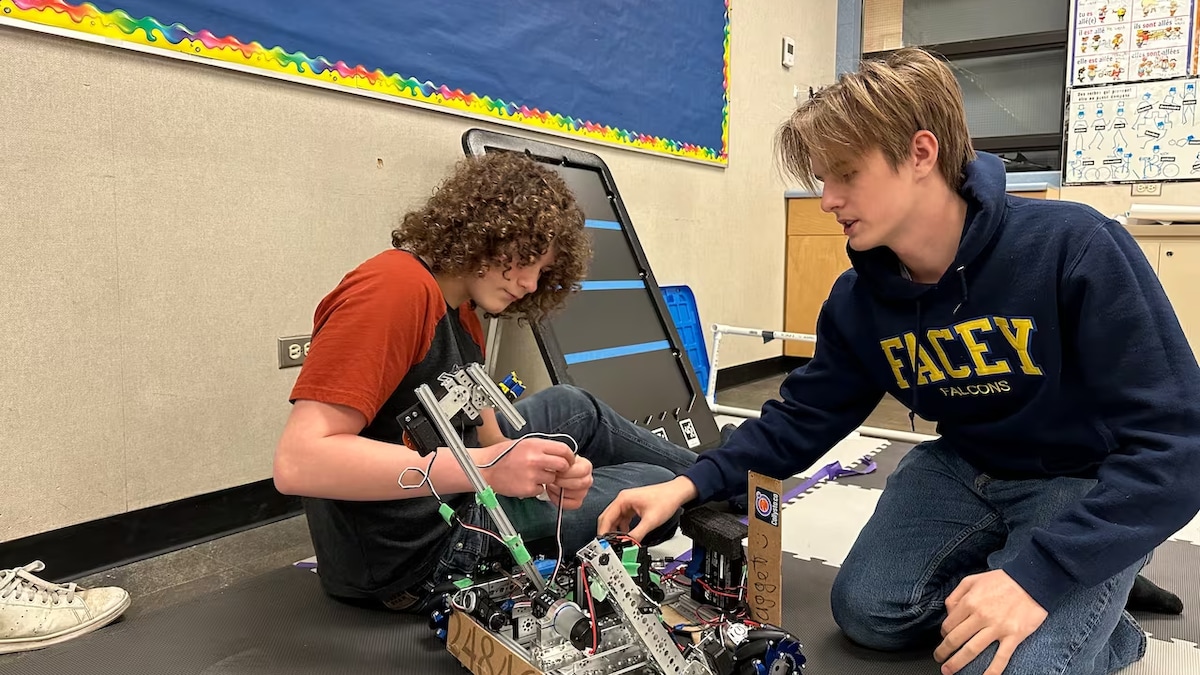 Deux élèves construisent une voiture robotique.