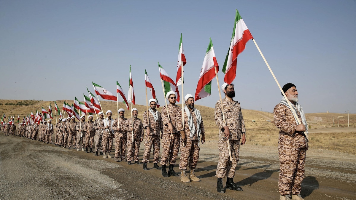 Des soldats en uniforme sont en file et tiennent tous un drapeau de l'Iran.