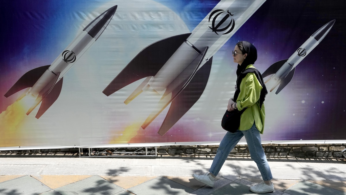 Une femme marchant devant une illustration représentant des missiles dans la capitale iranienne, Téhéran. (Photo d'archives)