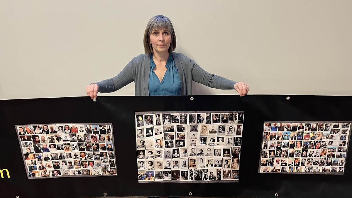 L'instigatrice du McIntyre Powder Project, Janice Martell, pose avec une bannière comprenant des photos de mineurs qui ont été touchés par l'utilisation de la poudre McIntyre.
