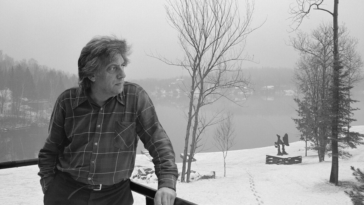 Jean Paul Riopelle, dans un paysage hivernal, regarde au loin.