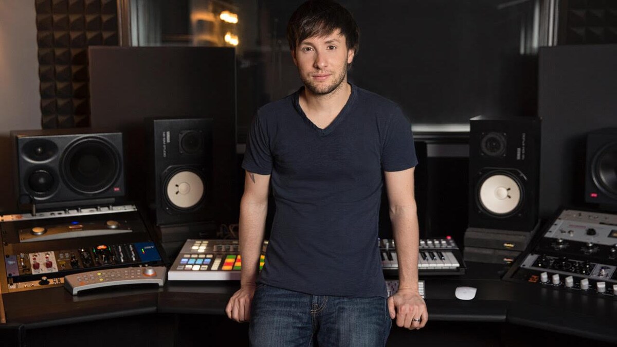 L'homme est debout devant des consoles de musique dans un studio.