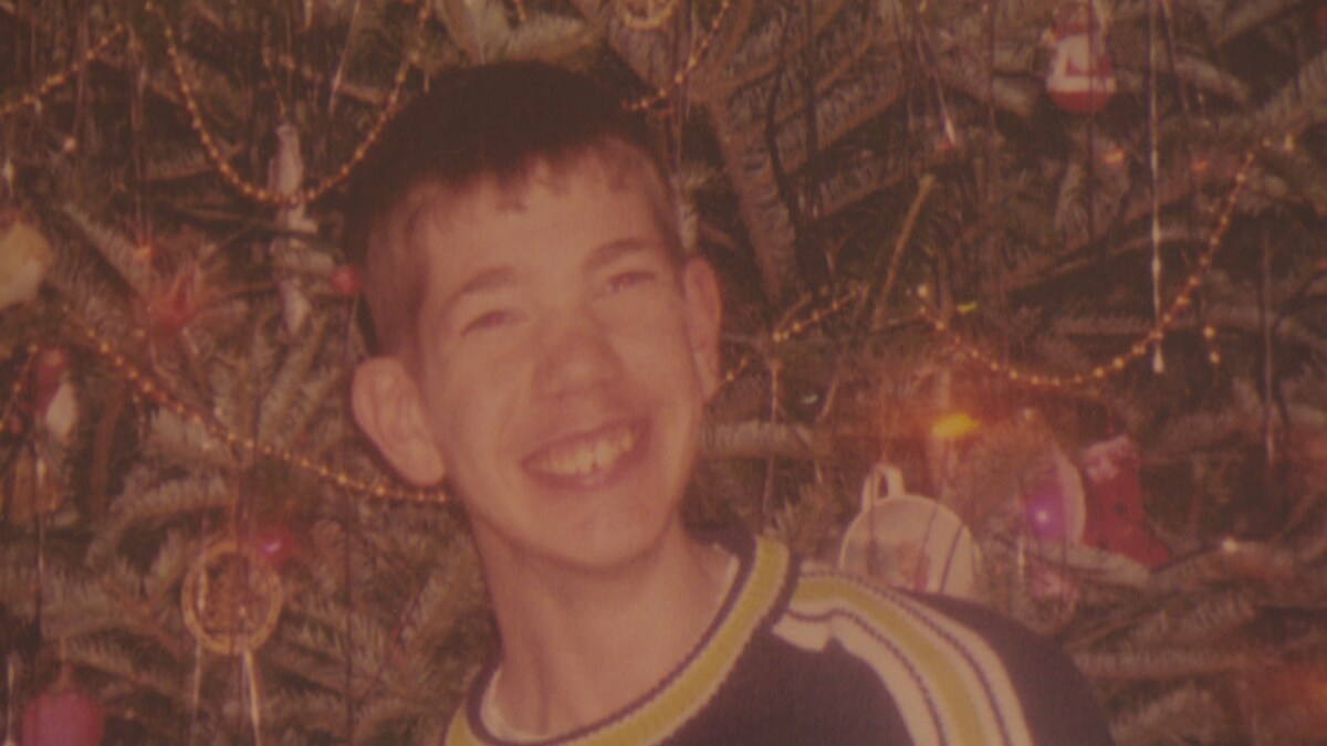 Photo de Joshua, tout sourire devant un sapin de Noël.