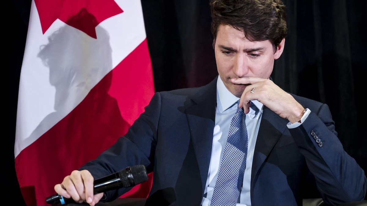 Justin Trudeau, un micro en main, semble fixer le sol.