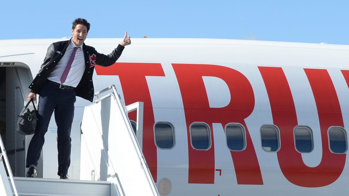 Justin Trudeau tient son pouce en l'air au haut de la rampe d'accès menant à l'avion du Parti libéral du Canada.