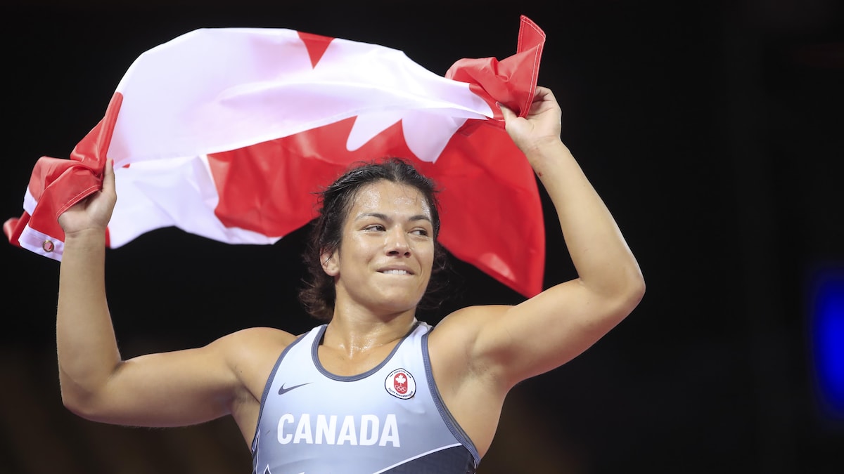 Justina Di Stasio en habit de lutte tient le drapeau du Canada.