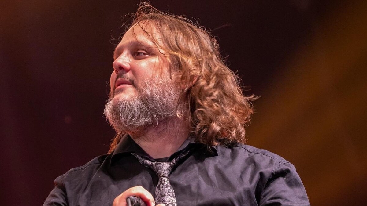 Le chanteur tient son micro sur scène. 