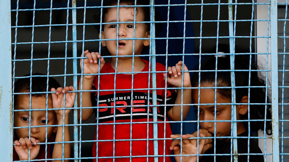 Des enfants derrière un grillage.