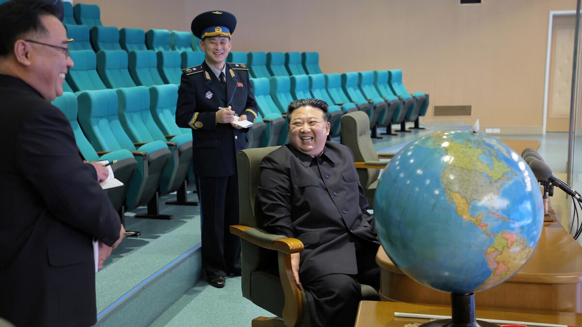 Kim Jung-un se montre réjoui en compagnie de trois personnes, devant un globe terrestre.