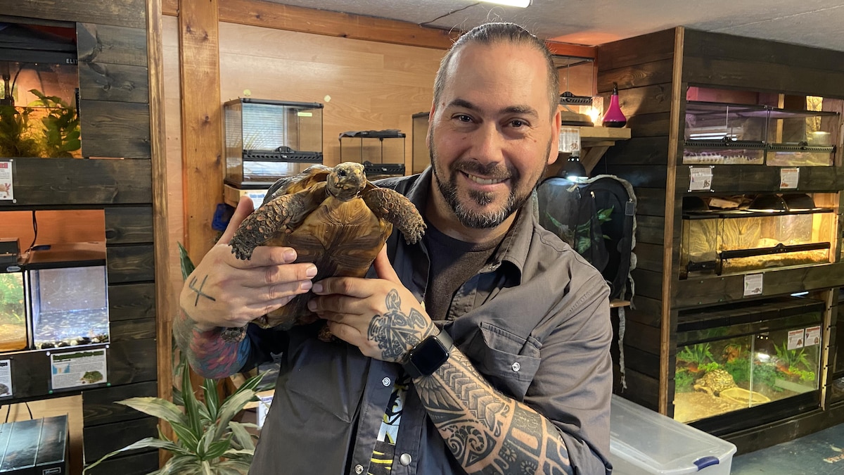 Tommy St-Laurent pose pour la caméra en tenant une tortue dans ses mains.