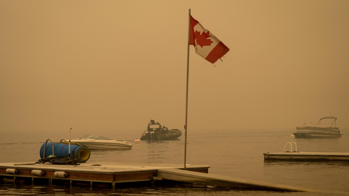 Un bateau de la GRC navigue sur le lac Shuswap sous une épaisse fumée en provenance du feu Adams Lake, en Colombie-Britannique.