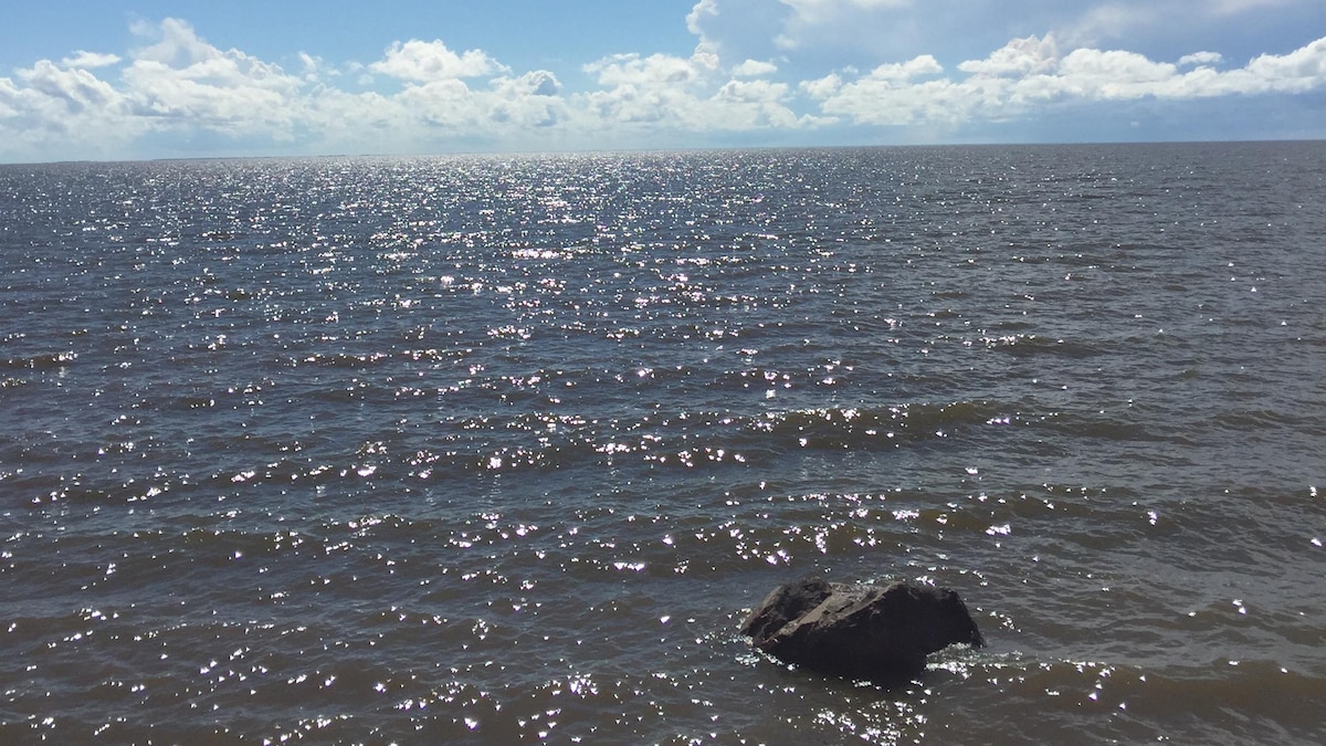 Le lac Winnipeg a quelques vagues pendant une journée ensoleillée. Le ciel est dégagé avec des nuages au loin. 