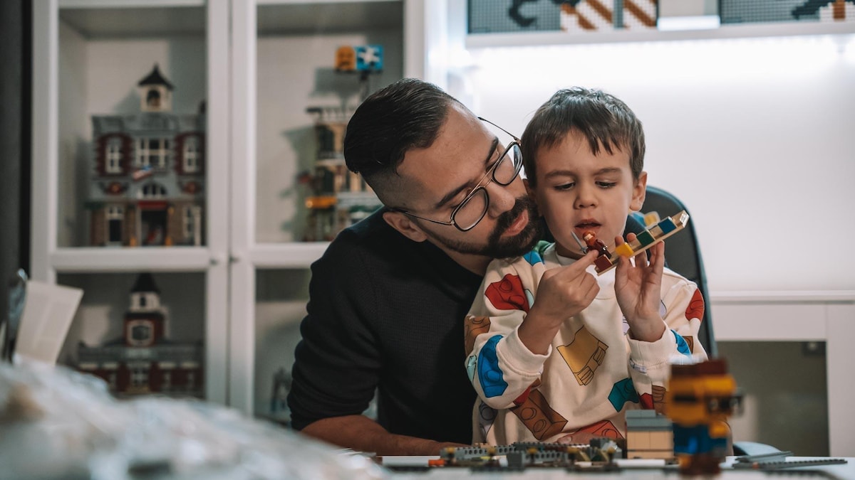 Il regarde un Lego avec son fils sur ses genous.