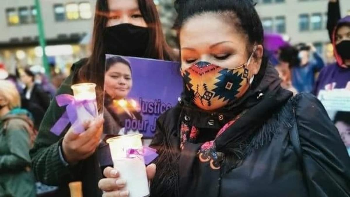 Nicole Awashish porte un masque et tient une affiche avec la photo de Joyce Echaquan.