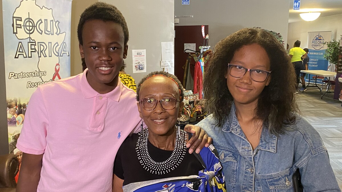 Trois personnes de la même famille se tiennent debout en souriant. 