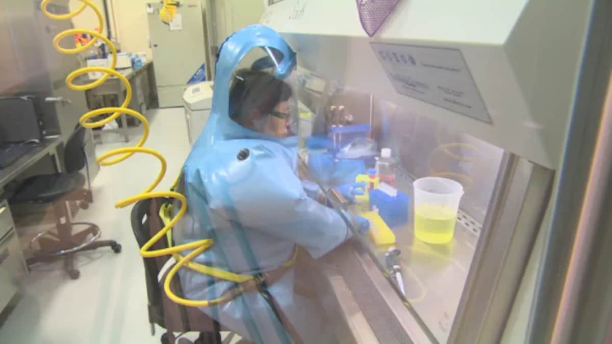 La Dre Xiangguo Qiu, vêtue de vêtements de protection à sécurité maximale, travaille dans le Laboratoire national de microbiologie de Winnipeg.