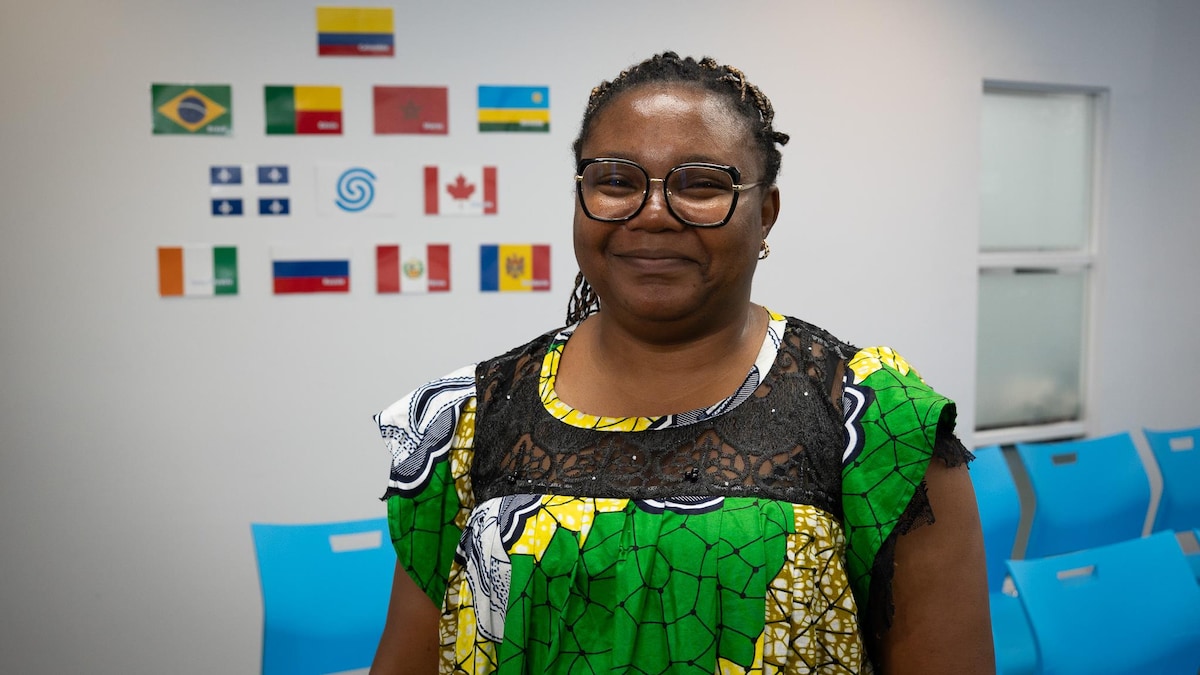 Madeleine Ngo Essola est tout sourire. Elle pose devant le logo du SITO et les drapeaux d’une dizaine de pays.