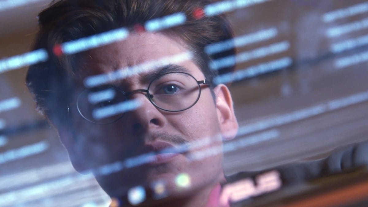 Un homme portant des lunettes regarde son reflet dans un écran d'ordinateur.