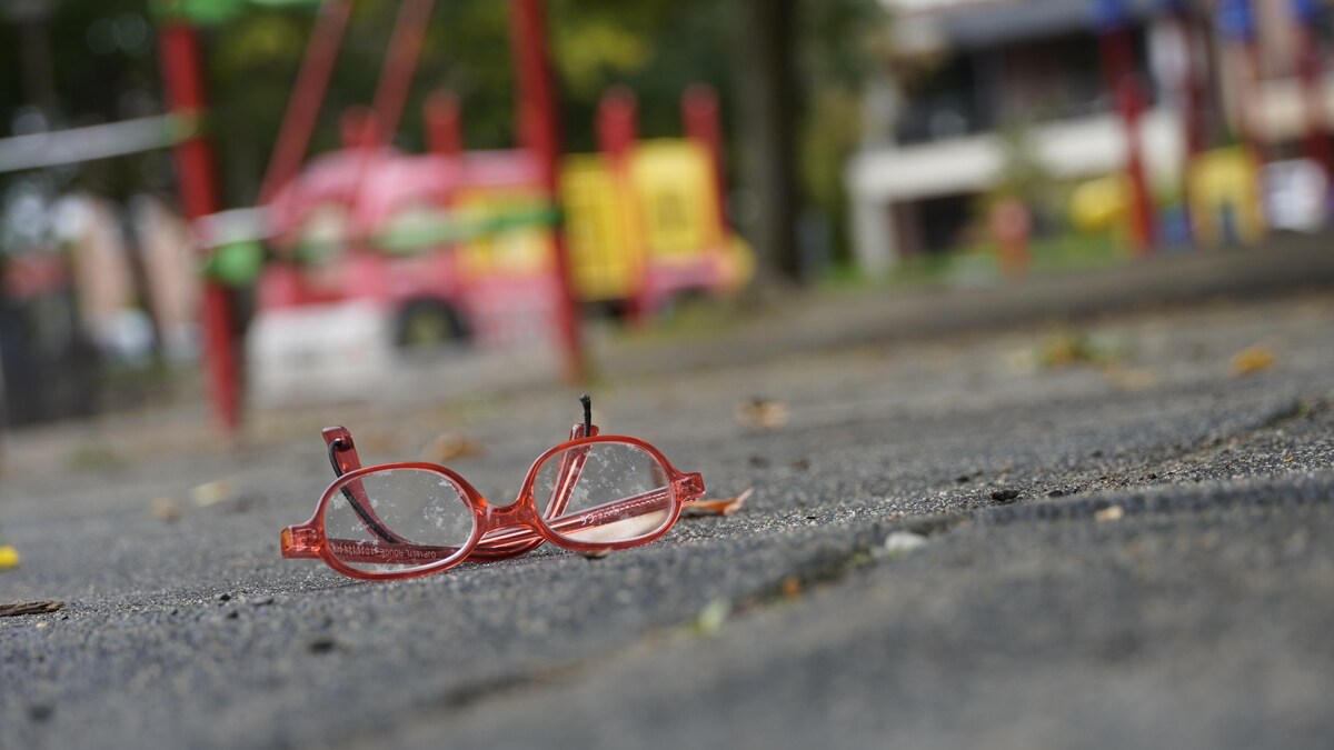 Des lunettes rouges pour enfants sont posées par terre dans une plaine de jeux.
