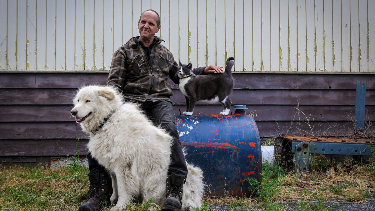 Pierre Quévillon sourit avec son chien Indica et son chat, le 20 juin 2023.