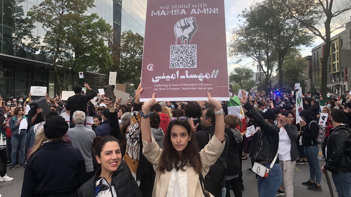 Une manifestante porte une pancarte sir laquelle on peut lire  : «Nous sommes avec Mahsa Amini».
