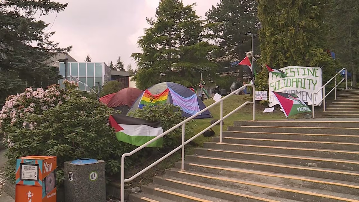 Des tentes, des drapeaux et des pancartes sur une pelouse.