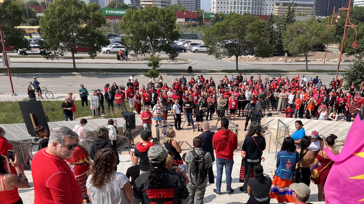 Des manifestants vêtus de rouge devant le Musée canadien pour les droits de la personne, le 17 août 2023. 