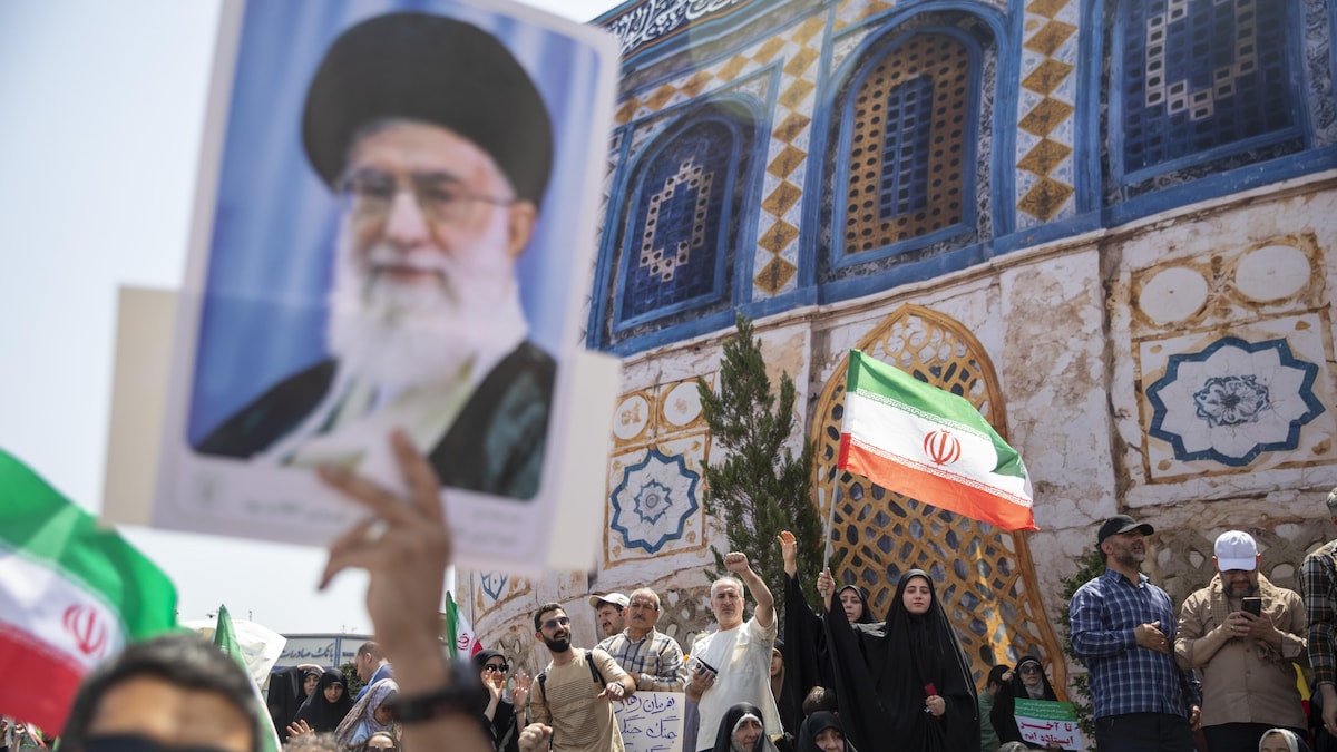 Des manifestants à Téhéran brandissent des drapeaux iraniens et un portrait du guide suprême iranien.