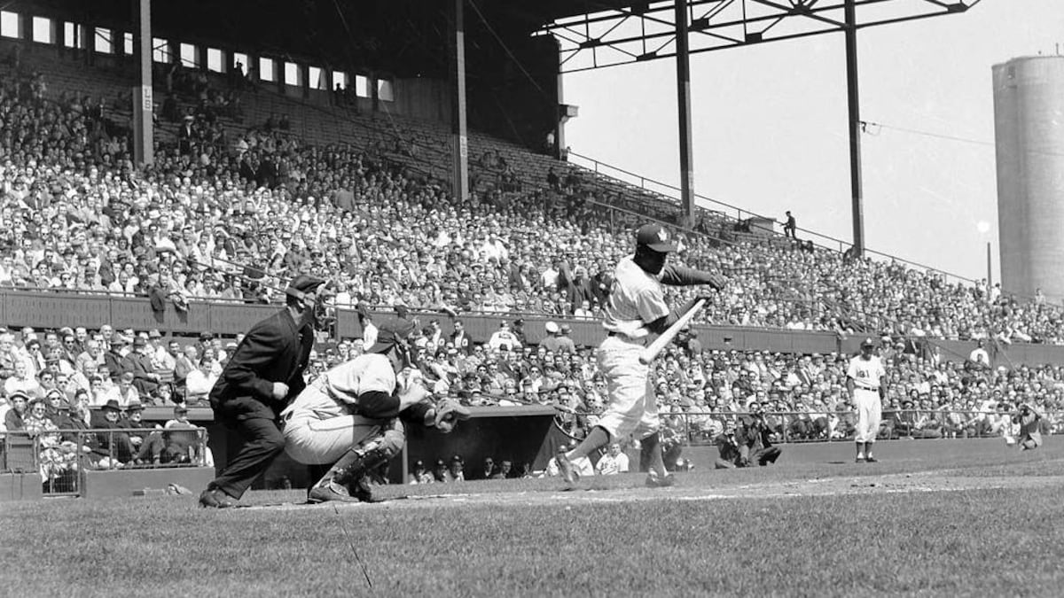 Un joueur de baseball au bâton lors d'un match avec une grande foule lors d'une autre époque.
