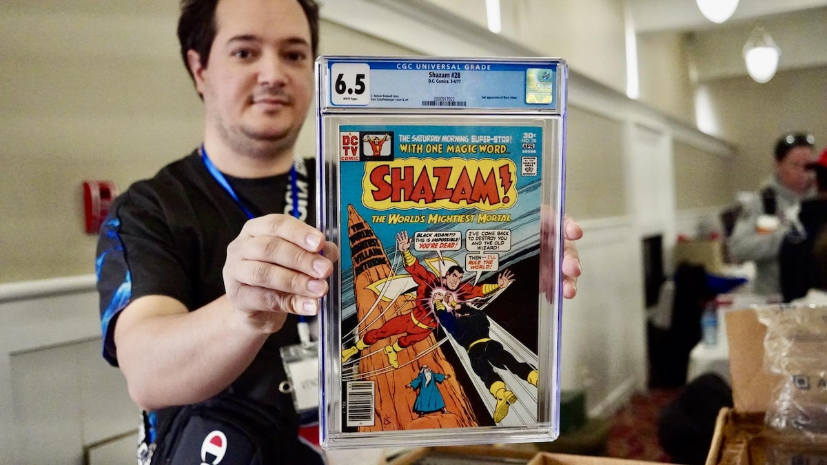 Un homme tient une copie d'une bande dessinée du superhéros Shazam.