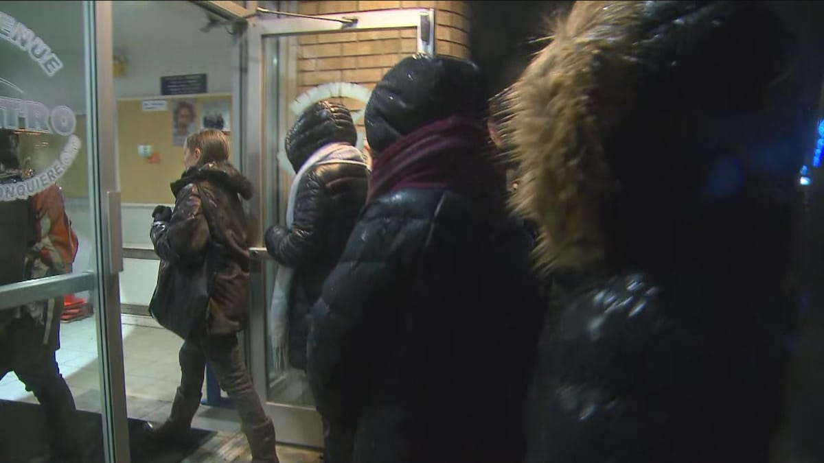 Des femmes avec des manteaux d'hiver entrent dans un édifice.