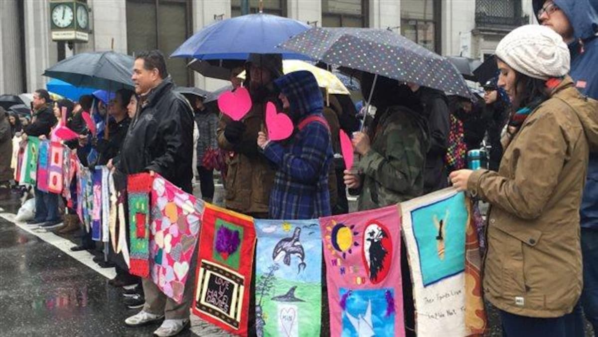 Des dizaines de personnes marchent sous la pluie dans le quartier Downtown Eastside de Vancouver, le 14 février 2016, en hommage aux femmes autochtones disparues ou assassinées.   