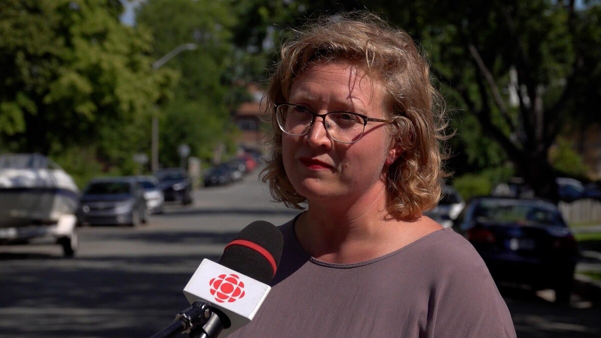 Marie-Hélène Massy Émond, en entrevue au micro de Radio-Canada, une rue et des arbres en arrière-plan.