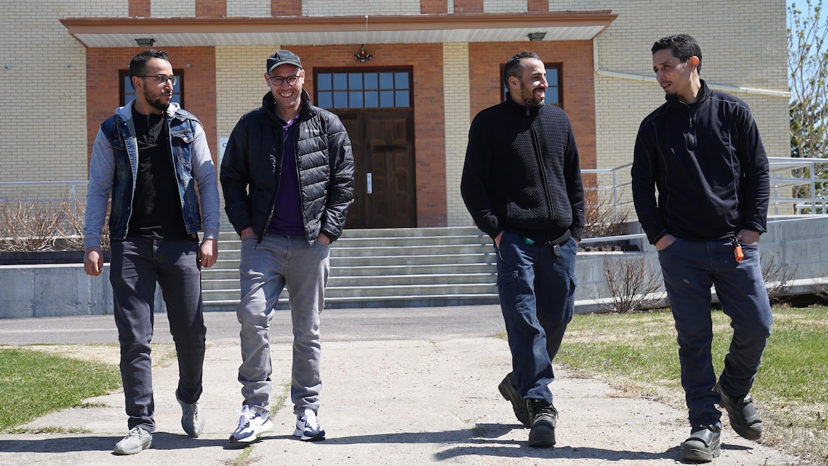 Quatre hommes marchent devant une église.