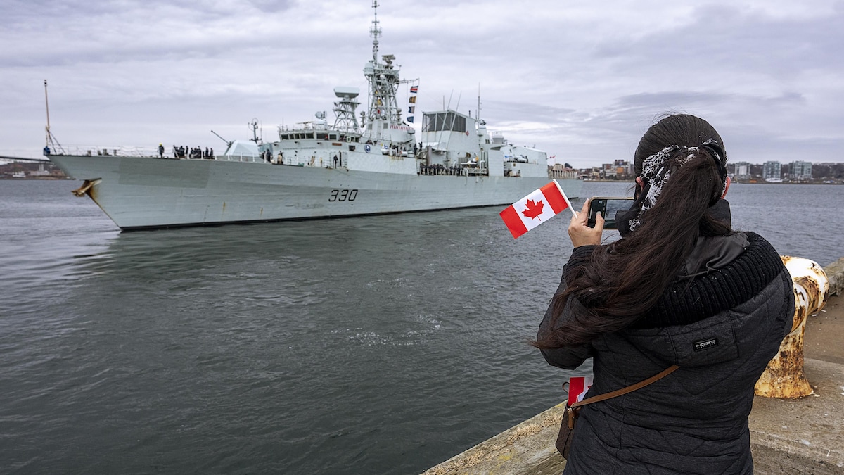 Une femme prend une photo alors que le NCSM Halifax quitte Halifax pour appuyer les mesures de dissuasion de l'OTAN en Europe de l'Est.