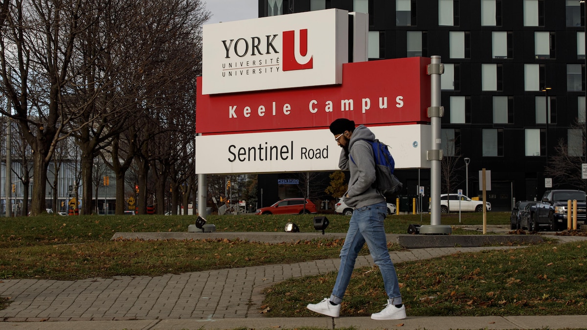 Un étudiant marche devant le panneau de l'Université York.
