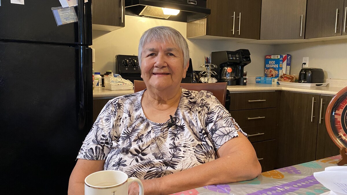 May Desnomie est assise dans la cuisine de son appartement, à Regina.
