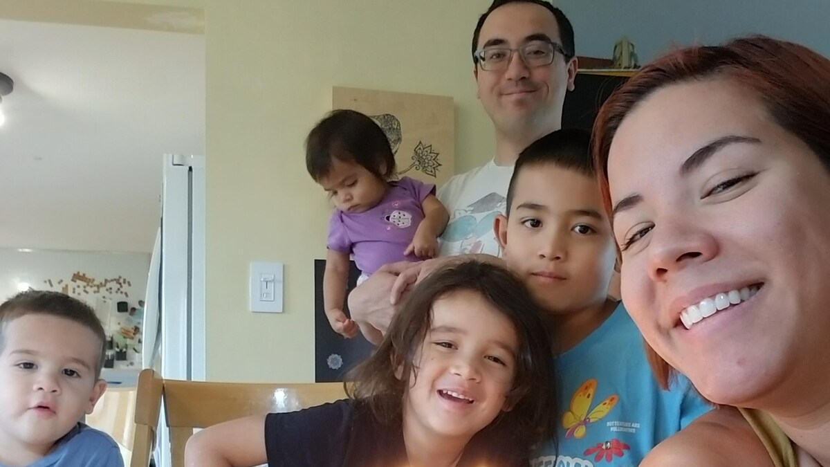 Égoportrait de la famille. Il y a les parents et les quatre enfants. Ils sont autour d'une table de la cuisine. Il y a un gâteau sur la table avec des bougies.
