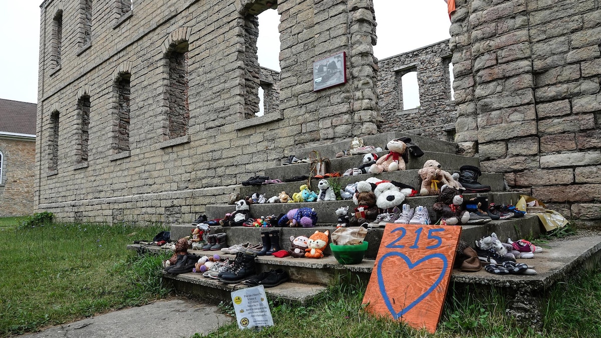 Des souliers et des jouets sont disposés sur les marches d'un bâtiment en ruines.