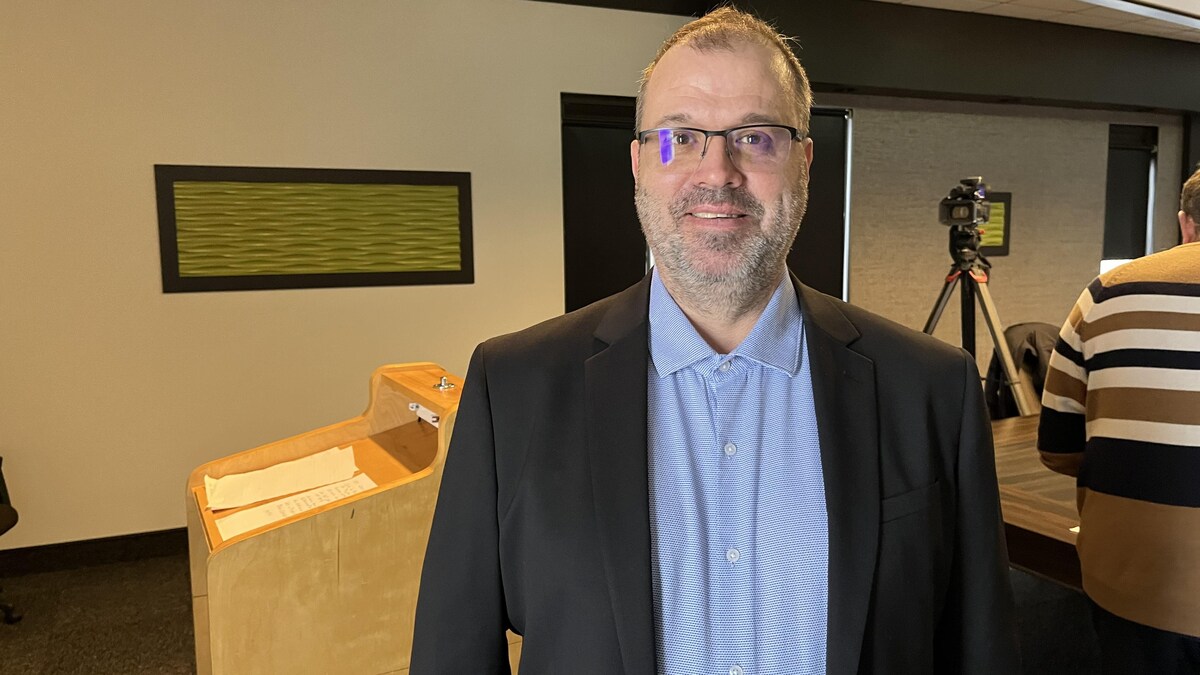 Michel Desbiens sourit pour la photo dans une salle de conférence.