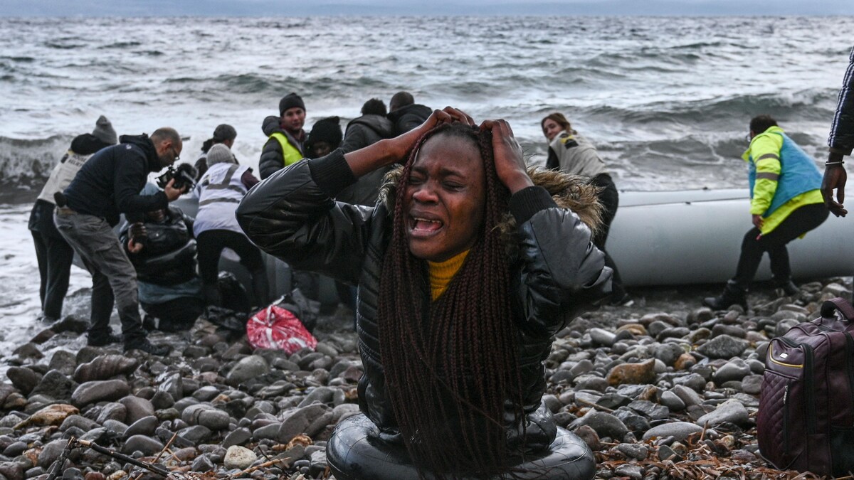 Une femme noire pleure sur le bord d'une plage.