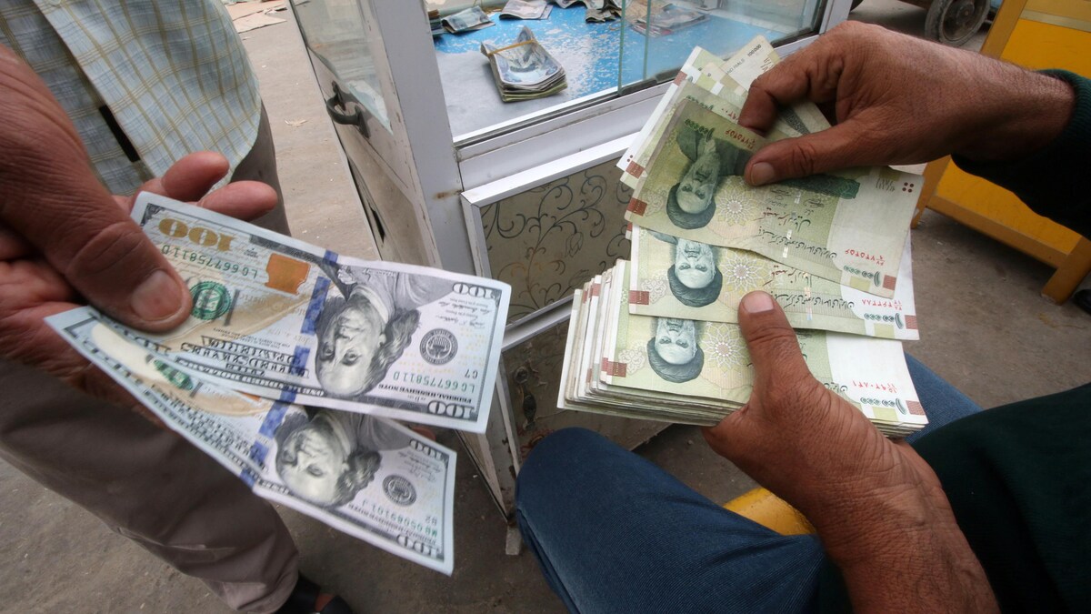 Un homme échangeant des dollars américains contre des rials iraniens dans un bureau de change à Téhéran.