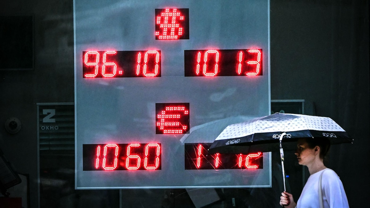  Une femme, tenant un parapluie, passe devant un bureau de change à Moscou le 14 août 2023. 