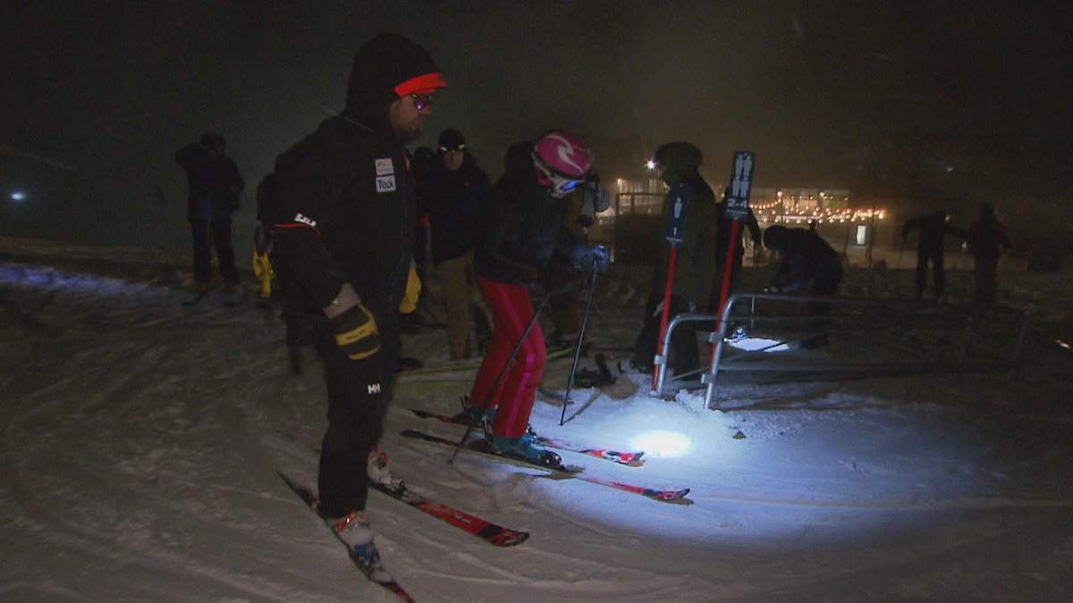 Des skieurs avancent avec leur lampe frontale.