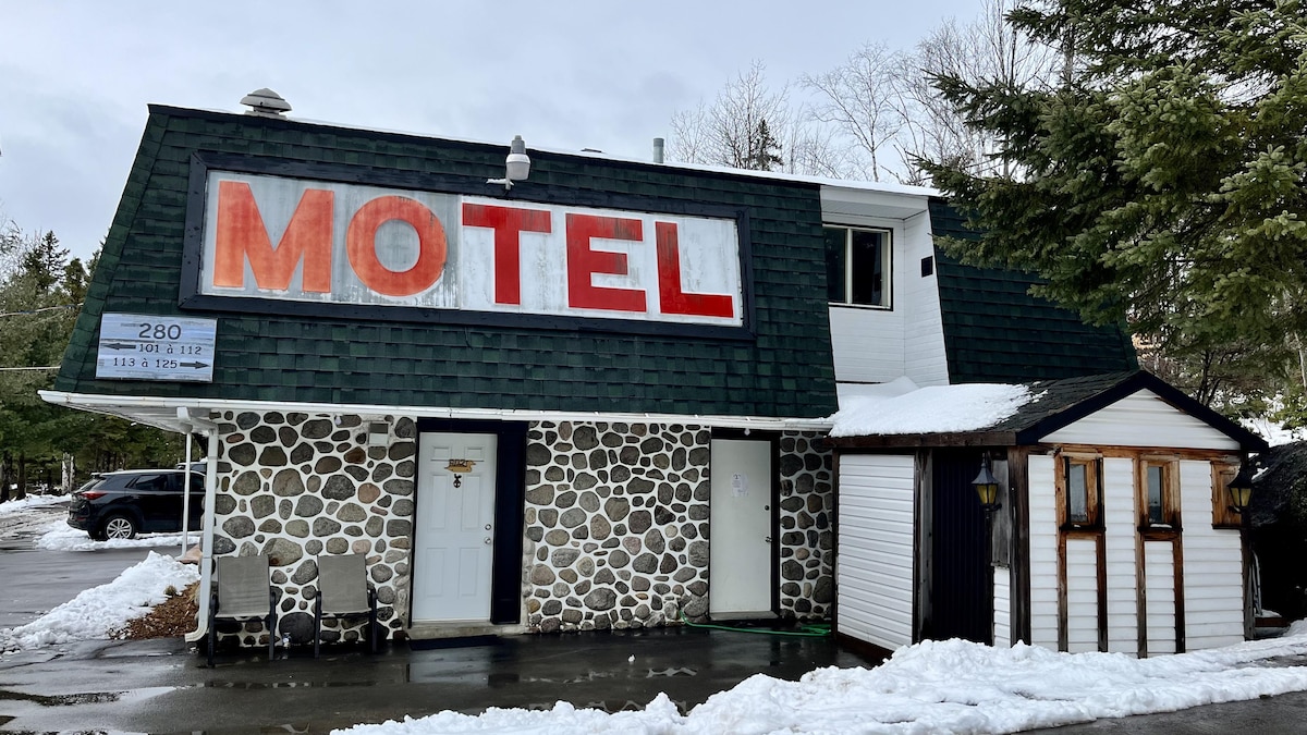 Une façade de motel un peu défraîchie avec une architecture qui rappelle les années 80.