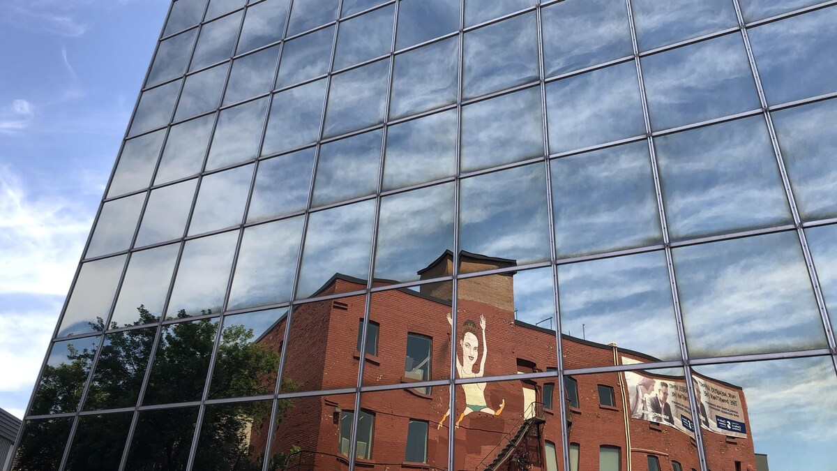 Le reflet d'une murale dans les fenêtres d'un bâtiment.