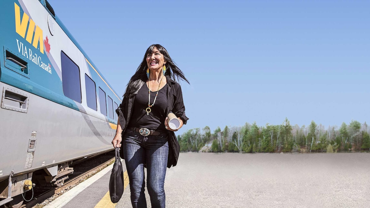 Une femme tenant un sac marche près d'un train.