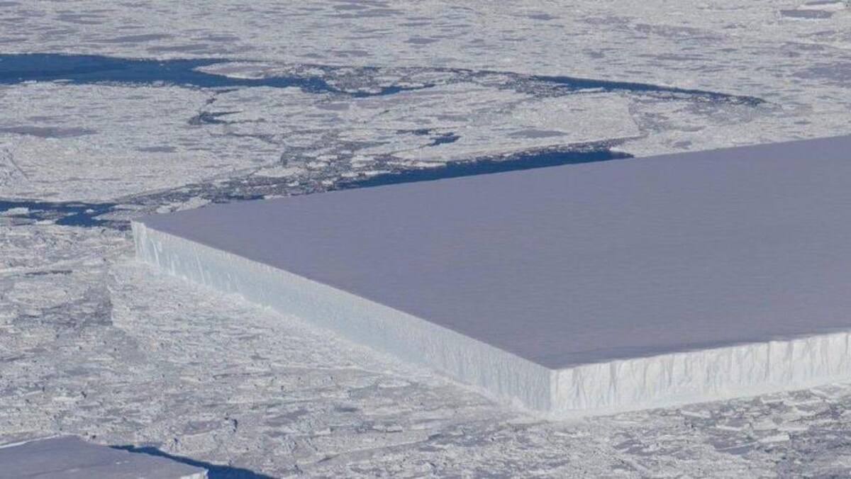 Un iceberg de forme plutôt rectangulaire au milieu d'autres glaces dans l'océan.