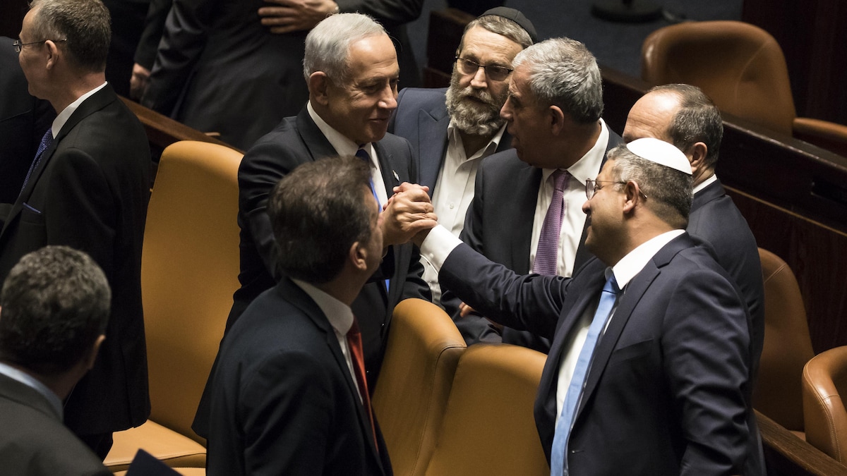 Deux hommes entourés d'un groupe d'hommes se serrent la main.